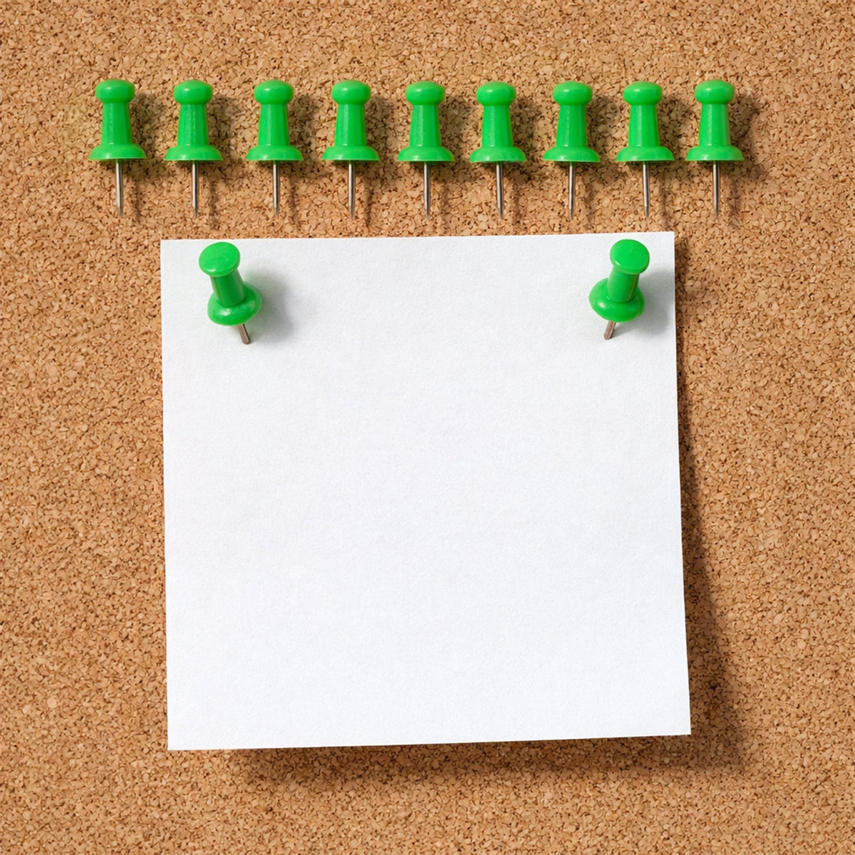 Green push pin fixing paper on a cork notice board
